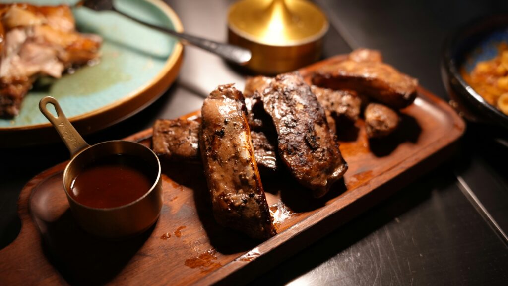 Oven-baked ribs coated with barbecue sauce and served fresh on a baking tray.